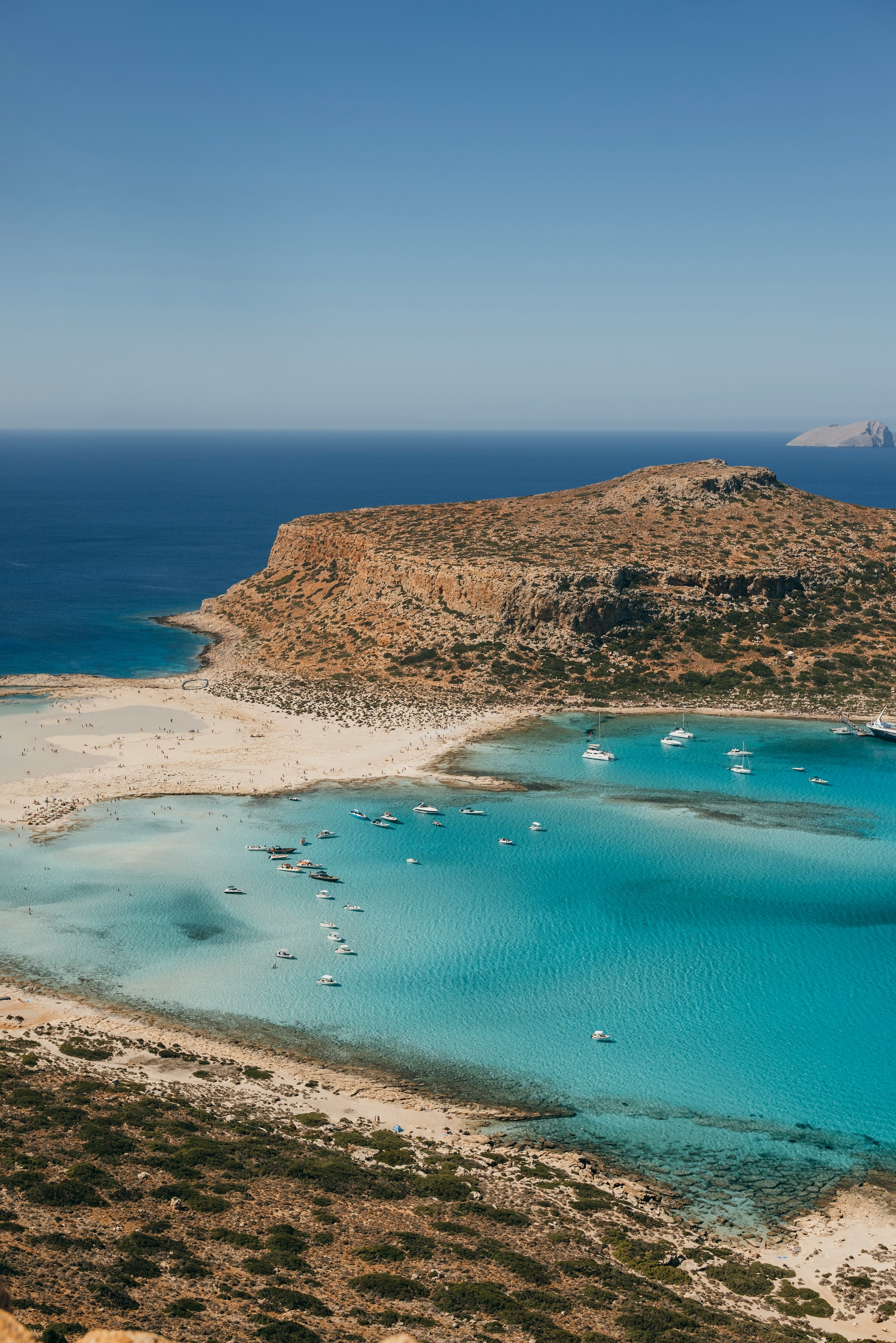 Kleine Boote in einer türkisfarbenen Bucht an der felsigen Küste Kretas